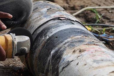 a person using a saw to cut a decommissioned pipe