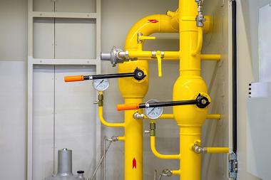 two yellow gas pipes with valves for safety and two pressure gauges